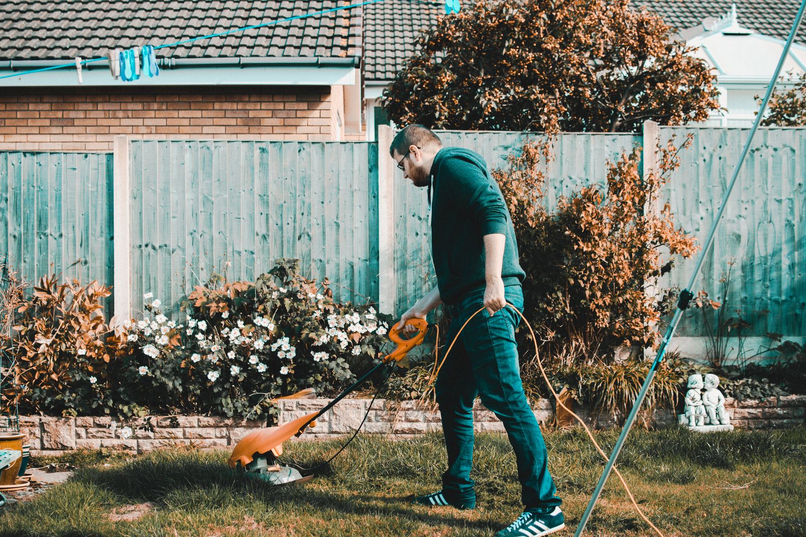 A person pushing a lawn mower across a garden lawn